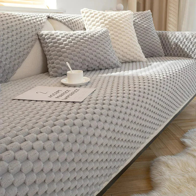 Gray textured sofa with cushions and a cup on a wooden floor.