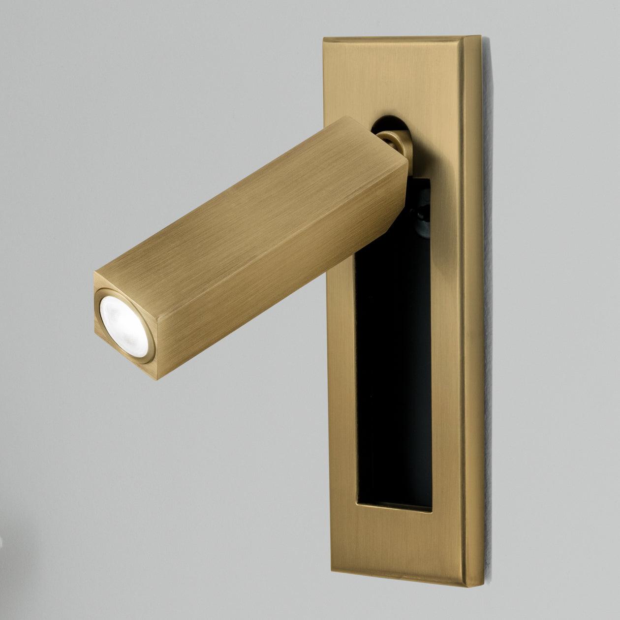 Gold wall light fixture on a gray background