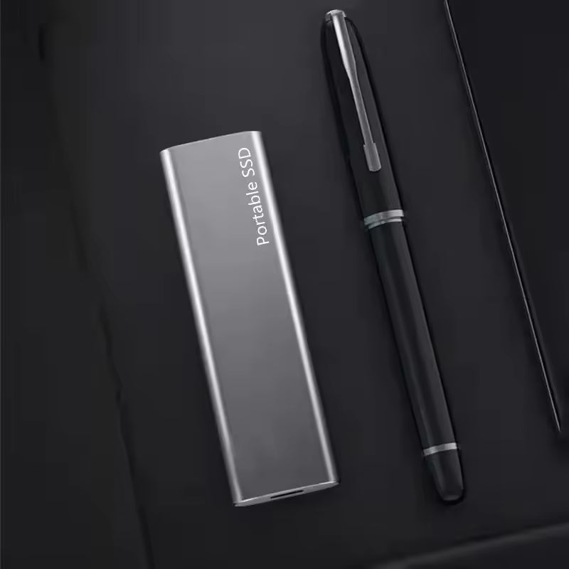 Portable SSD on a dark surface with a pen and notebook